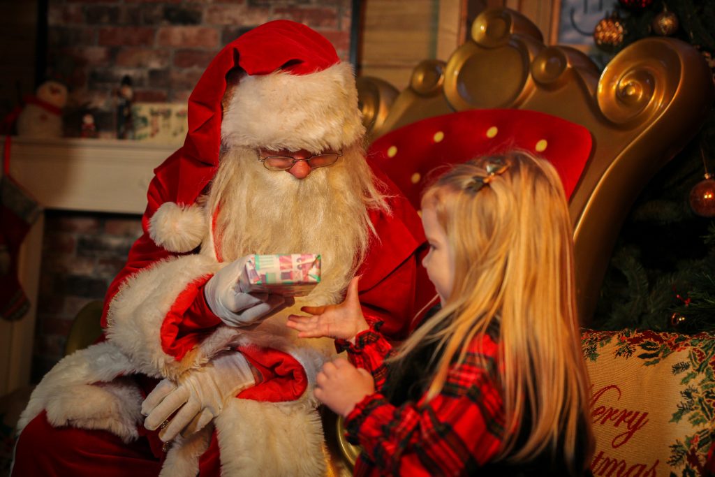Santa passing a wrapped toy to a child
